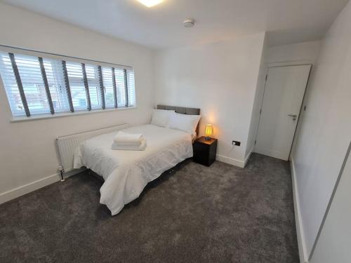 HornchurchElm Park Cheerful 4-Bedroom Holiday Home的卧室设有一张白色大床和一扇窗户。