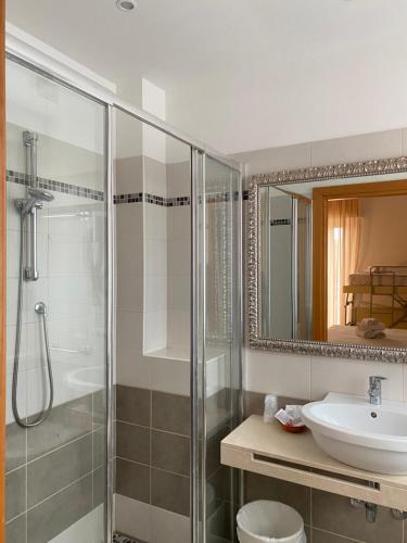 里米尼Hotel Ravello的带淋浴、盥洗盆和镜子的浴室