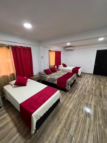 普罗维登西亚POSADA VILLA BRYAN的酒店客房,设有三张床和红色窗帘