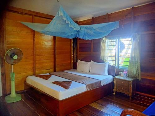 瓜隆岛班南简易别墅和餐厅宾馆的一间卧室配有一张蓝色天蓬床