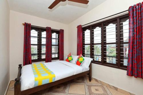 马迪凯里AAdya. Homestay的一间卧室设有一张床和两个窗户。