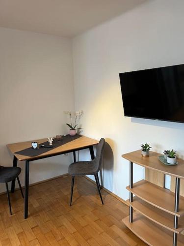 因斯布鲁克Einzimmerwohnung im Grünen/Innsbruck/2 PAX的桌子、椅子和墙上的电视