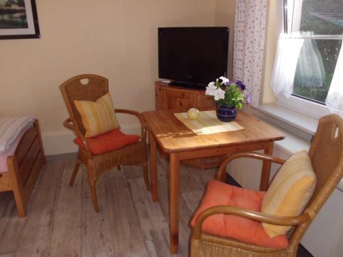 NeuenkirchenFerienwohnung Familie Maas的客厅配有桌椅和电视。