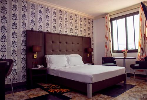 雅温得New Heaven Hôtel的一间卧室配有一张大床和大床头板