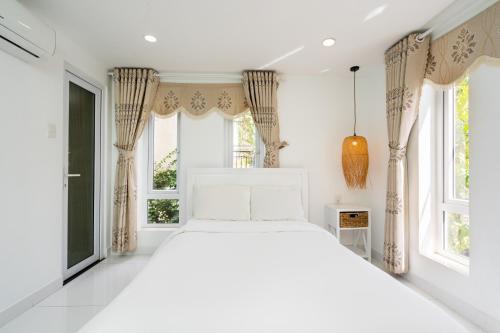 头顿Sunset Bãi Dâu Boutique Hotel Vũng Tàu的卧室配有白色的床和2扇窗户。
