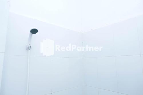 PampangFortuner Homestay Syariah Makassar Mitra RedDoorz的浴室墙上有红色的合作伙伴标志