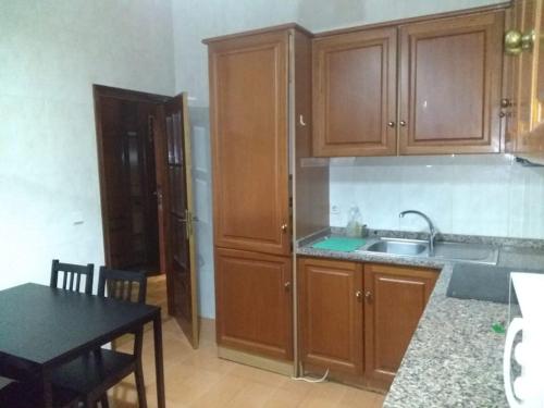 波尔图Flores Apartment的厨房配有木制橱柜、水槽和桌子