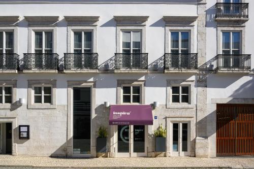 里斯本Inspira Liberdade Boutique Hotel的公寓大楼设有紫色遮阳篷