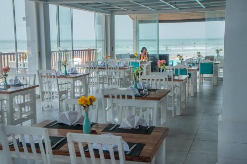Sere Kunda NDingSunset Beach Hotel的一间设有白色桌椅的餐厅以及海滩