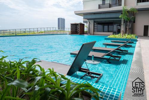马六甲Bali Premier Suites Melaka的一座带躺椅的游泳池位于大楼旁