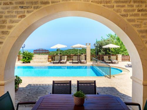 阿斯特里昂Family-Friendly Villa Erofili with Pool, Childrens Area & BBQ!的拱门,在游泳池上方,配有桌椅