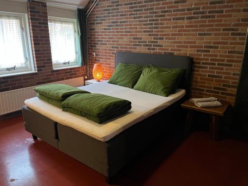 迪弗尔Familiehuis的一间卧室配有一张带绿色枕头的床和砖墙
