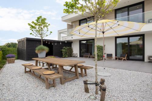 栋堡Hello Zeeland - Summum Suites的庭院设有木桌、长凳和遮阳伞。