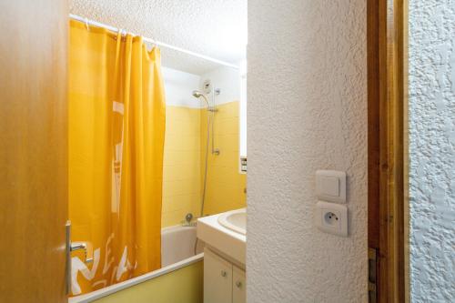 贝勒沃Le Forchat - proche des pistes的浴室设有黄色的淋浴帘和水槽