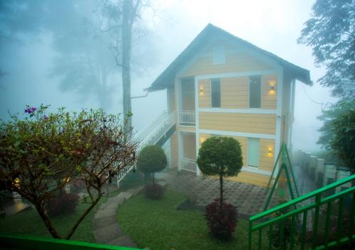 蒙纳Areva Inn Munnar by VOYE HOMES的雾中的房子,房子
