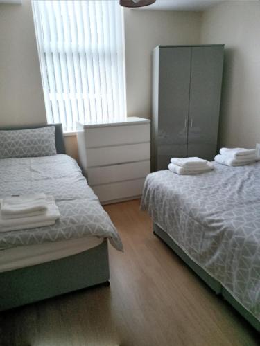 利物浦Sandringham House的一间卧室配有两张床、一个梳妆台和橱柜。