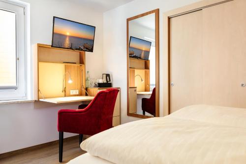 黑尔戈兰岛Helgolandia Dependance的一间卧室配有一张床、一张红色椅子和一面镜子