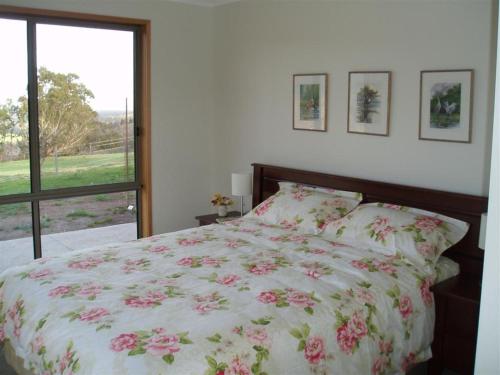 Mafeking马弗晶鹰景别墅的一间卧室配有一张带花卉床罩的床和窗户。