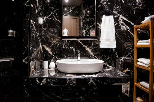 雅典Stylish Apartment, Acropolis view的浴室设有白色水槽和黑色大理石墙壁。
