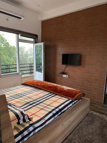瓦拉纳西Kaashi Flora - Luxury 3BHK的一间卧室设有一张大床,砖墙上配有电视
