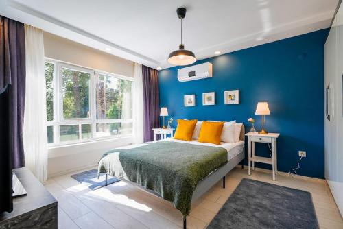 安塔利亚Modern Flat near Hadrian's Gate的一间卧室拥有蓝色的墙壁,配有一张带橙色枕头的床。