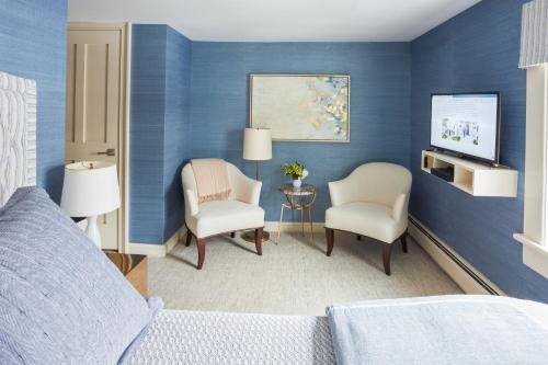 莱诺克斯33 Main的一间卧室设有蓝色的墙壁、两把椅子和电视