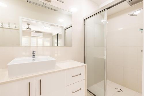 科莱特Sandy Beach House Corlette Unit 1 Waterfront WI-FI Aircon的白色的浴室设有水槽和淋浴。