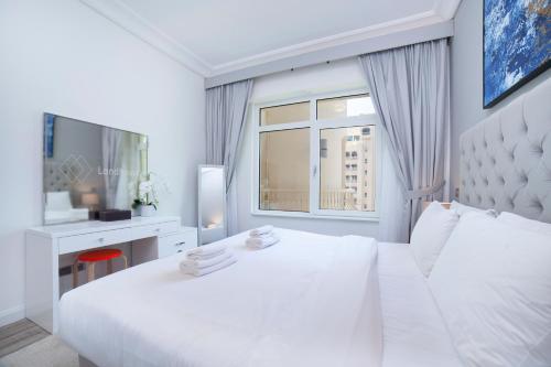 迪拜Lux Living on Palm Jumeirah With Beach Access & Complimentary Golf的白色的卧室设有一张白色大床和一个窗户。