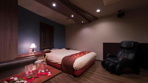 东京Hotel Will池袋 Adult Only的一间卧室配有一张床、一把椅子和一张桌子