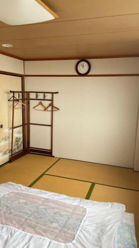 和歌山はらビジネス旅館的一间设有一张床和墙上一个时钟的房间