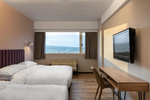 恒春古城河堤垦丁渡假酒店的酒店客房设有三张床、一张桌子和电视。