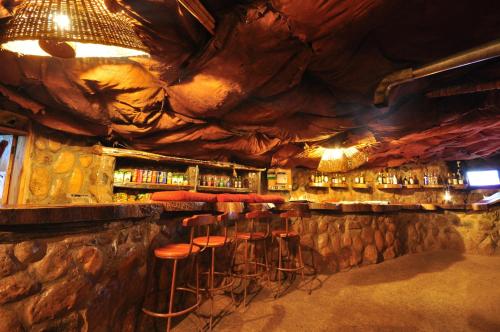埃尔多雷特Naiberi River Campsite & Resort的一个带凳子的酒吧,位于一个设有岩石墙的房间