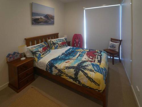 Cape WoolamaiModern air-conditioned 3-bedroom townhouse in centre of Cape Woolamai的一间卧室,床上有棕榈树