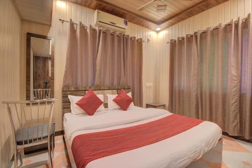 阿利鲍格Hotel Snehaprabha - Near to Nagaon Beach Alibaug的一间卧室配有一张带红色枕头的床和一把椅子