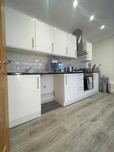 弗特威克Flitwick Luxury Apartment - Sleeps 4的厨房铺有木地板,配有白色橱柜。