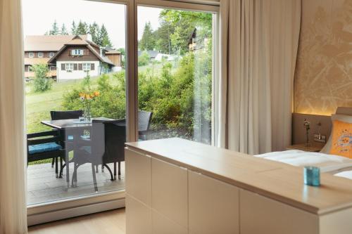 魏森湖Strandhotel am Weissensee的客房设有大窗户和餐桌。