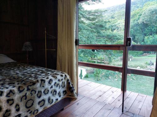 奥索里乌Recanto da Paz - Aos pés do Morro da Borússia的一间卧室设有一张豹纹床和一个大窗户
