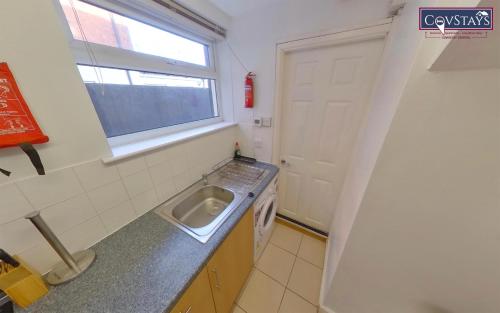 考文垂City Retreat - 1-bed Apartment in Coventry City Centre的一个带水槽和窗户的小厨房
