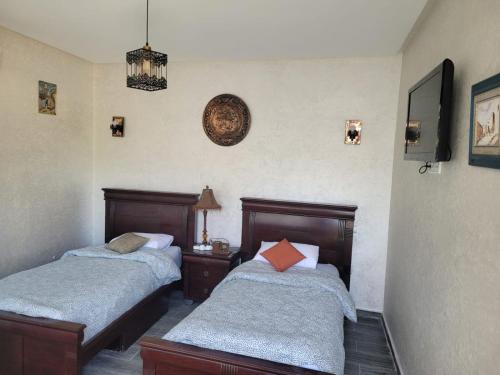 卡萨布兰卡Jnane Ville Verte的一间卧室设有两张床,墙上挂着一个时钟。