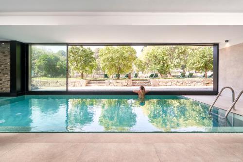 阿尔库什迪瓦尔德维什Ribeira Collection Hotel by Piamonte Hotels的妇女在带大窗户的游泳池里