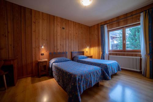 尚波吕克Family Apartments Le Chalet的配有木墙和窗户的客房内的两张床