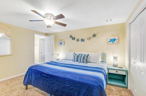 泰比岛Tybee Southern Comfort的一间卧室配有蓝色的床和吊扇