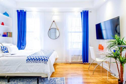 纽约62-3B Studio Prime UES Walk to Central Park的一间卧室配有蓝色窗帘、一张床和电视。