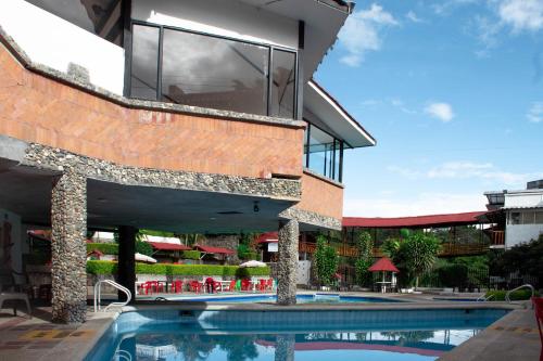 ChachagüíLa Gran Estancia Hotel Campestre的一座带游泳池的建筑和一座带窗户的建筑