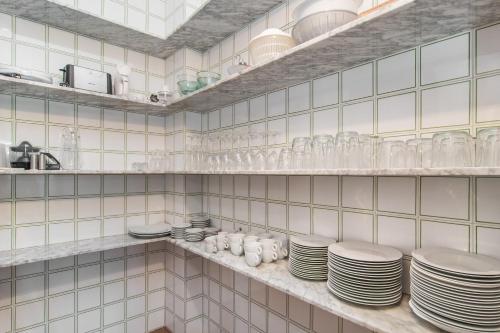 克里斯托港ES GANXO HOUSE PORTO CRISTO的白色瓷砖厨房,架子上放有盘子和玻璃杯