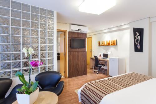 圣湖镇Ramada Hotel & Suites Lagoa Santa By Wyndham的酒店客房带一张床、一张桌子和椅子