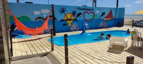 圣若泽-达科罗阿格兰迪Pousada Lá Na Praia的一座游泳池,里面的人有壁画