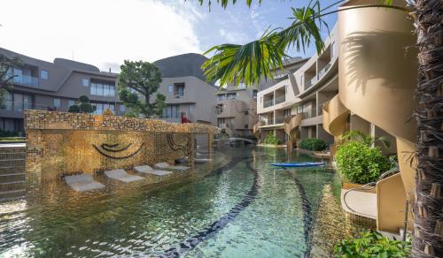 卡塔海滩Metadee Concept Hotel的庭院中一座游泳池,庭院内有建筑
