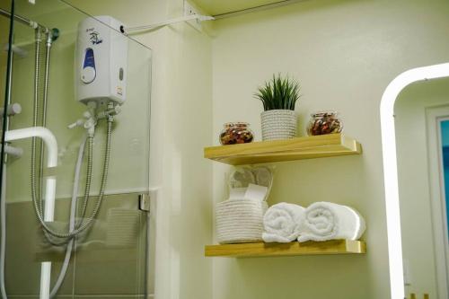 大雅台Vicar Home by Serin East Tagaytay的浴室设有木制架子、毛巾和淋浴。