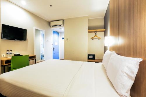 日惹Hotel Citradream Tugu Yogyakarta的卧室配有一张白色大床和一张书桌